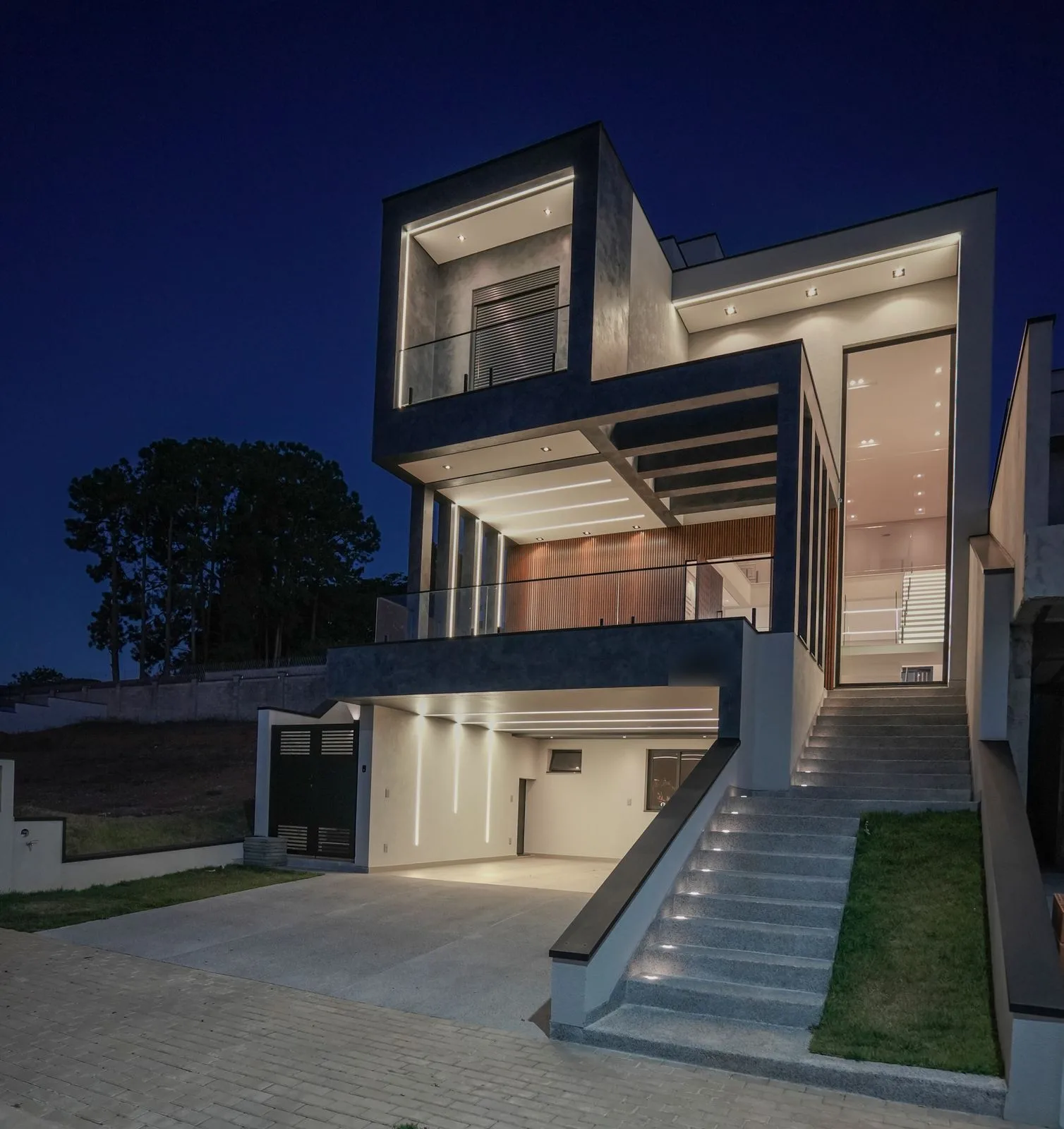 Fachada de residência à noite com perfis de LED e escada iluminada