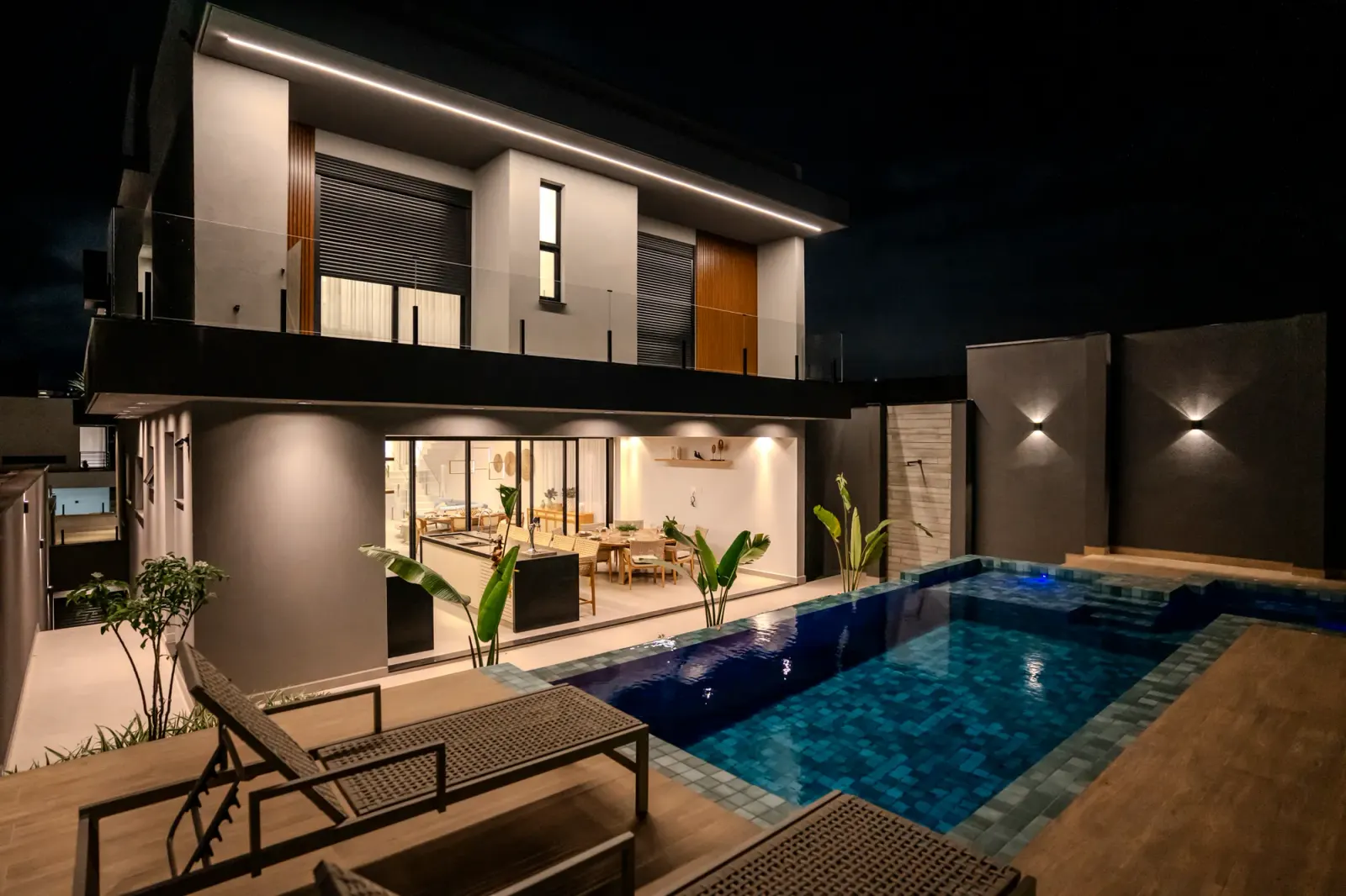 Área externa e piscina iluminadas à noite
