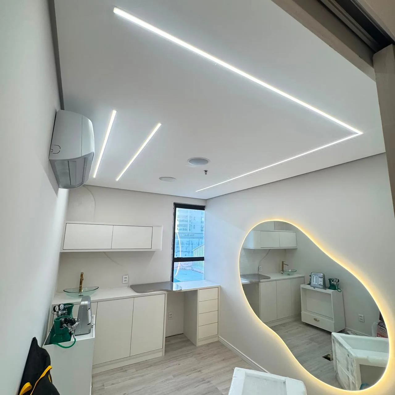 Consultório com perfis de LED no forro e espelho com luz indireta