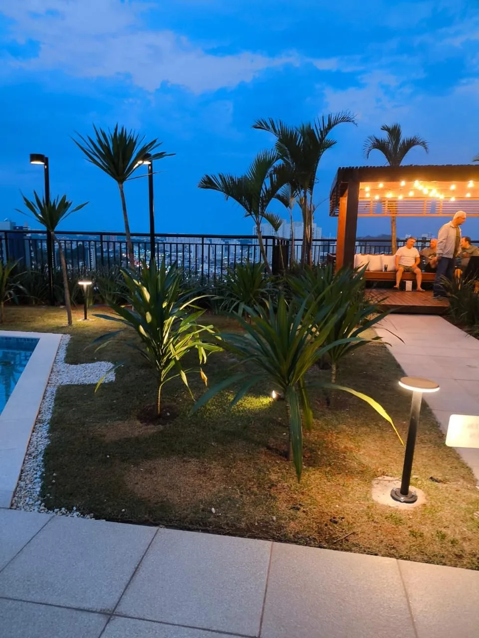 Jardim do condomínio ao entardecer com balizadores e gazebo iluminado