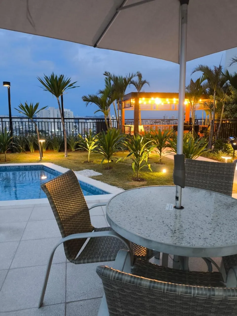 Área de lazer com gazebo iluminado e piscina